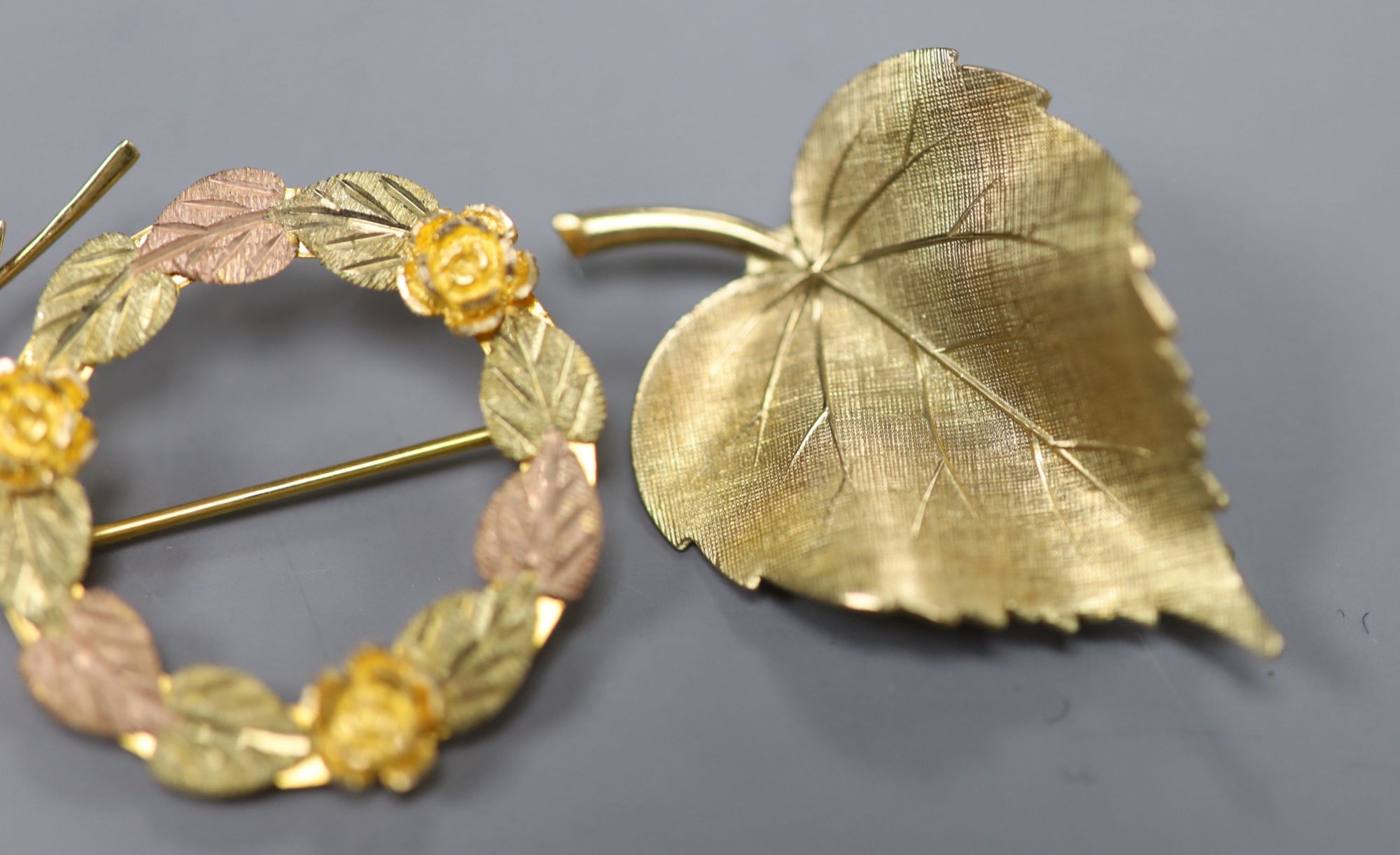 A 585 yellow metal double leaf brooch, 51mm a 9ct gold leaf brooch and a 10k tri-colour foliate wreath brooch (3)